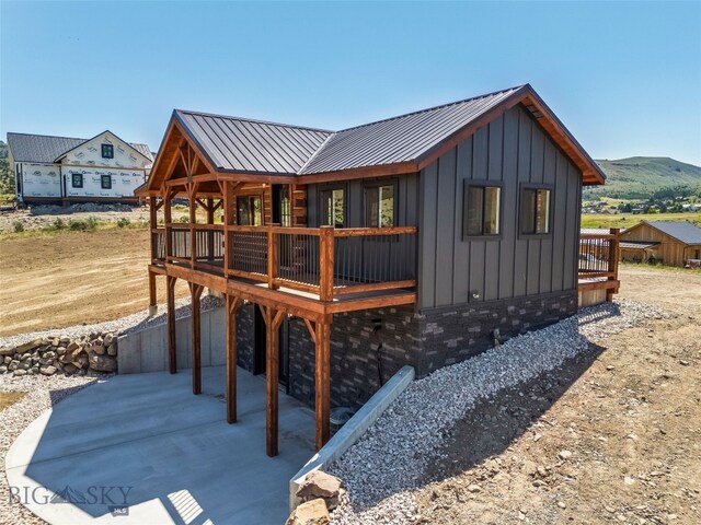 209 W Madison St, Virginia City, MT 59755 - rear view of property with board and batten siding, a patio, a deck with mountain view, and a metal roof