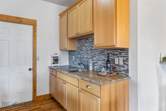 34 W Katina Ct, Bozeman, MT 59718 - kitchen with decorative backsplash, light brown cabinets, dark stone countertops, and light wood-style flooring