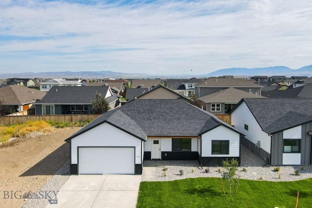 1511 Pistolero Way, Belgrade, MT 59714 - view of front facade featuring a residential view, an attached garage, concrete driveway, a shingled roof, and a mountain view
