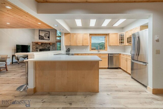 8 Ringneck Dr, Big Sky, MT 59716 - kitchen with appliances with stainless steel finishes, light brown cabinetry, light wood finished floors, light countertops, and a fireplace