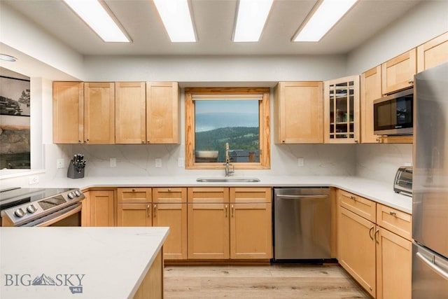 8 Ringneck Dr, Big Sky, MT 59716 - kitchen featuring appliances with stainless steel finishes, light brown cabinetry, tasteful backsplash, light wood-style flooring, and light countertops