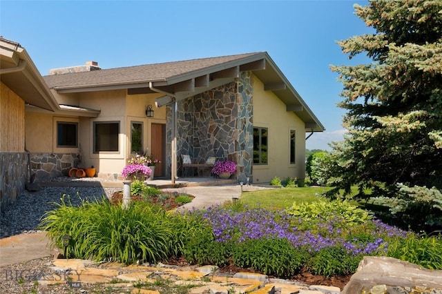 1520 Black Bull Trl, Bozeman, MT 59718 - back of house with stone siding, a chimney, and stucco siding