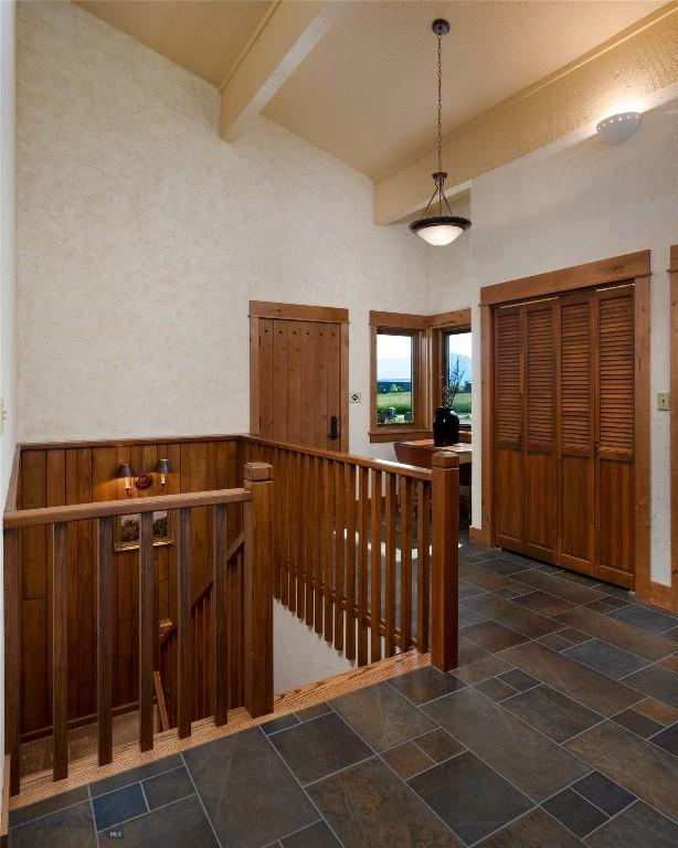 1520 Black Bull Trl, Bozeman, MT 59718 - entrance foyer with beamed ceiling, high vaulted ceiling, dark stone finish flooring, and a wainscoted wall