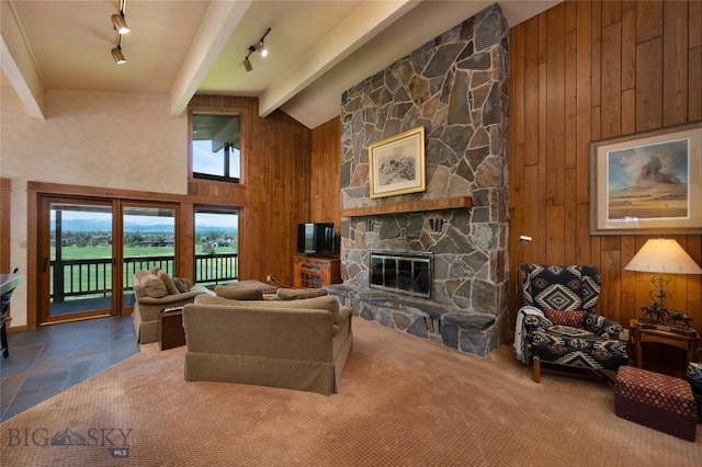 1520 Black Bull Trl, Bozeman, MT 59718 - living room featuring track lighting, wood walls, beamed ceiling, high vaulted ceiling, and a fireplace