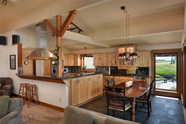 1520 Black Bull Trl, Bozeman, MT 59718 - kitchen with wall chimney range hood, light brown cabinets, dark countertops, backsplash, and a chandelier