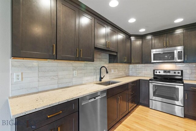 2757 Marlyn Ct Unit 1, Bozeman, MT 59718 - kitchen featuring appliances with stainless steel finishes, light stone counters, dark brown cabinetry, decorative backsplash, and recessed lighting
