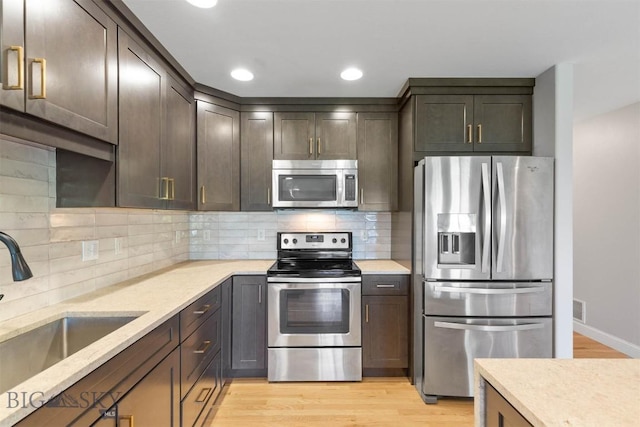 2757 Marlyn Ct Unit 1, Bozeman, MT 59718 - kitchen with appliances with stainless steel finishes, light wood-style flooring, tasteful backsplash, recessed lighting, and light stone counters