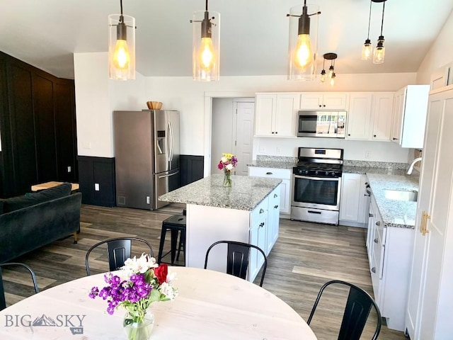801 Pleiades Pl, Livingston, MT 59047 - kitchen with appliances with stainless steel finishes, wood finished floors, white cabinetry, light stone countertops, and a center island