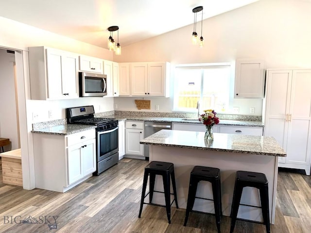801 Pleiades Pl, Livingston, MT 59047 - kitchen with appliances with stainless steel finishes, lofted ceiling, a breakfast bar, a kitchen island, and light wood-type flooring