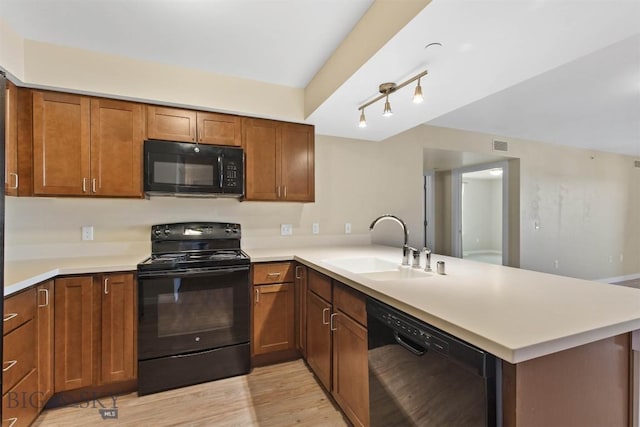 210 S Cottonwood Rd Unit 308, Bozeman, MT 59718 - kitchen with black appliances, a peninsula, light countertops, light wood-type flooring, and brown cabinets