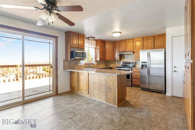 34 Mammoth Dr, Butte, MT 59701 - kitchen featuring stainless steel appliances, a peninsula, under cabinet range hood, decorative backsplash, and brown cabinets