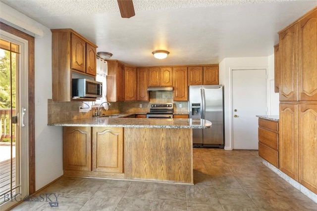 34 Mammoth Dr, Butte, MT 59701 - kitchen with stainless steel appliances, a peninsula, under cabinet range hood, tasteful backsplash, and light stone countertops