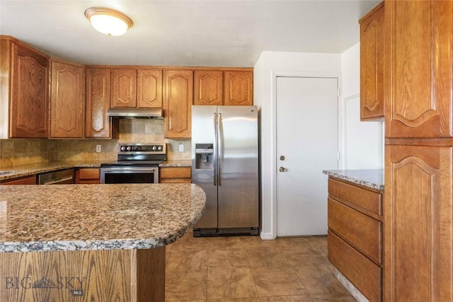 34 Mammoth Dr, Butte, MT 59701 - kitchen featuring stainless steel appliances, under cabinet range hood, brown cabinetry, tasteful backsplash, and light stone counters