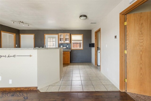 735 10th St, Butte, MT 59701 - kitchen featuring glass insert cabinets, brown cabinetry, and light tile patterned flooring