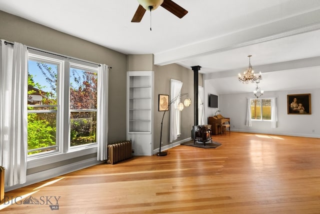 606 S Washington St, Dillon, MT 59725 - unfurnished living room with a wood stove, radiator, plenty of natural light, a chandelier, and beamed ceiling