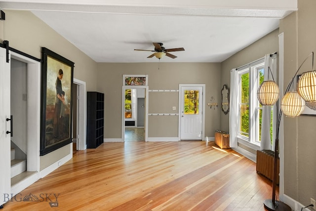 606 S Washington St, Dillon, MT 59725 - spare room with light wood-type flooring, a ceiling fan, and a barn door