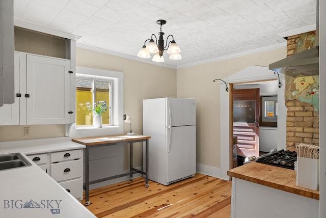 606 S Washington St, Dillon, MT 59725 - kitchen featuring freestanding refrigerator, light wood-type flooring, ornamental molding, white cabinets, and a chandelier
