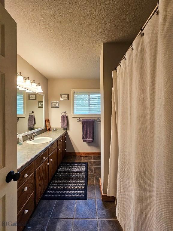 201 W 8th Ave, Big Timber, MT 59011 - full bath featuring vanity, healthy amount of natural light, a textured ceiling, tile patterned floors, and curtained shower