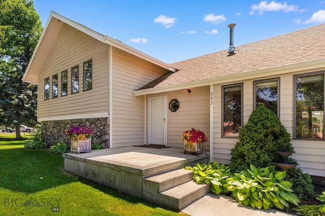 353 Sacajawea Peak Dr, Bozeman, MT 59718 - view of exterior entry featuring a yard, stone siding, and roof with shingles