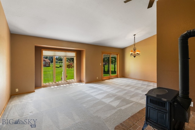 353 Sacajawea Peak Dr, Bozeman, MT 59718 - unfurnished living room with a wood stove, a chandelier, plenty of natural light, light carpet, and lofted ceiling