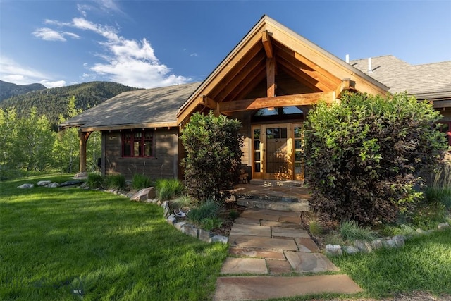 526 Chief Joseph, Big Sky, MT 59716 - view of exterior entry with a yard, a mountain view, and roof with shingles
