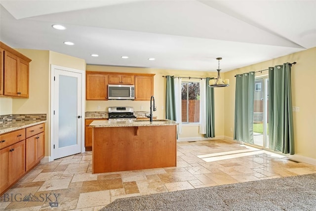 1705 Ingomar Blvd, Belgrade, MT 59714 - kitchen featuring stainless steel appliances, stone tile flooring, recessed lighting, light stone countertops, and an island with sink