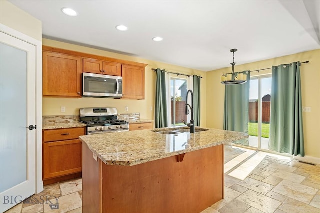 1705 Ingomar Blvd, Belgrade, MT 59714 - kitchen with appliances with stainless steel finishes, stone tile floors, a center island with sink, light stone counters, and recessed lighting