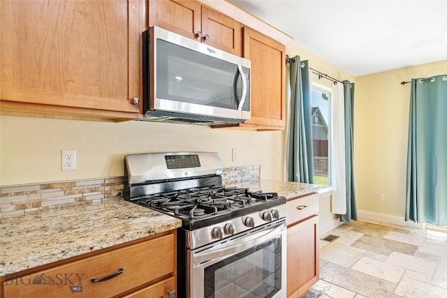 1705 Ingomar Blvd, Belgrade, MT 59714 - kitchen featuring stainless steel appliances, stone tile flooring, light stone countertops, and backsplash