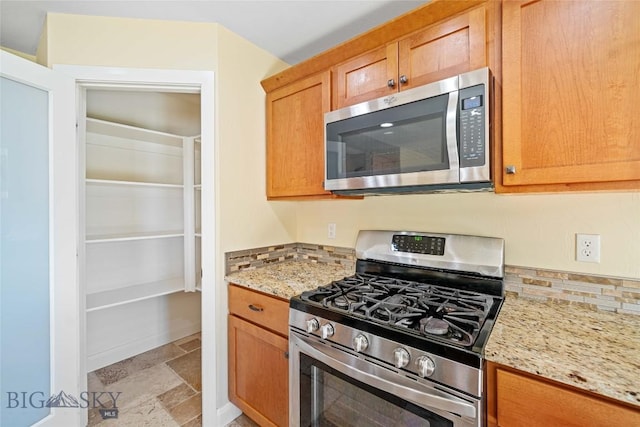 1705 Ingomar Blvd, Belgrade, MT 59714 - kitchen featuring stainless steel appliances, stone tile flooring, light stone counters, and decorative backsplash