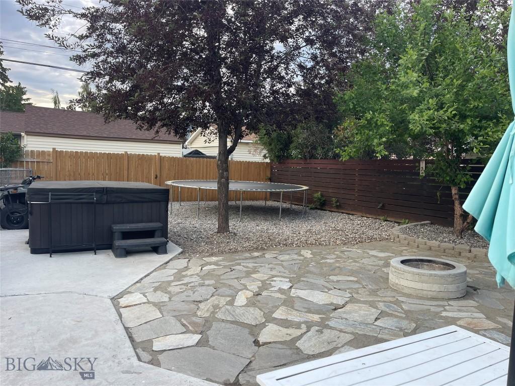 2625 St Ann St, Butte, MT 59701 - fenced backyard featuring a patio area, a trampoline, and a hot tub