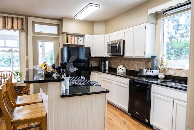 300 Holmes, Butte, MT 59701 - kitchen with black appliances, white cabinets, tasteful backsplash, a kitchen breakfast bar, and light wood-style flooring