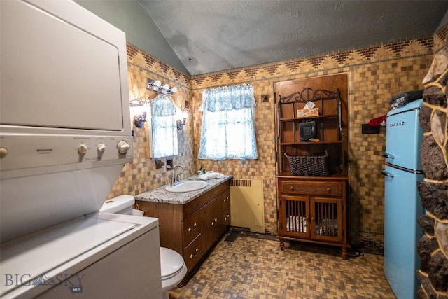 300 Holmes, Butte, MT 59701 - bathroom featuring estacked washer and dryer, vanity, vaulted ceiling, tile walls, and tile patterned floors