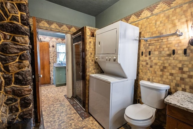 300 Holmes, Butte, MT 59701 - bathroom featuring estacked washer and dryer, tile walls, and a textured ceiling
