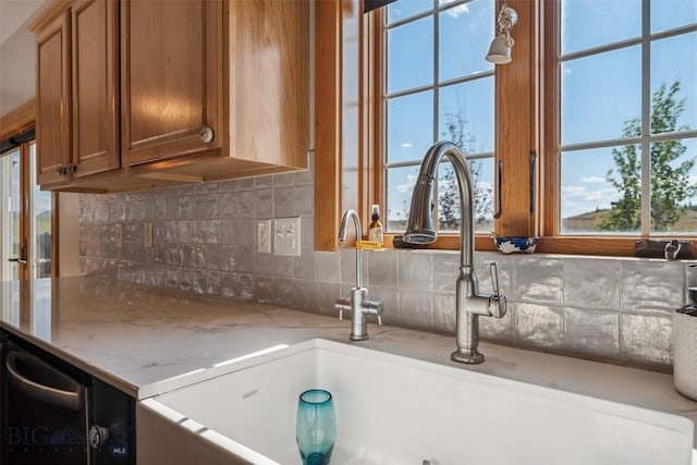 219 Rolling Glen Ranch Loop, Three Forks, MT 59752 - kitchen with brown cabinetry, tasteful backsplash, light stone countertops, and plenty of natural light