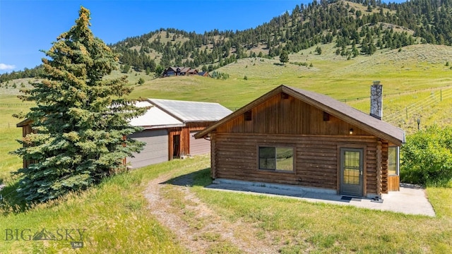 3500 Jackson Creek Rd, Bozeman, MT 59715 - view of front of home with log siding, a mountain view, a chimney, an outdoor structure, and a front yard
