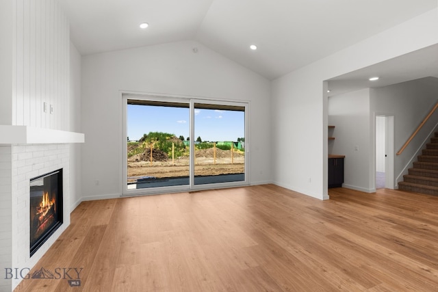 2809 S 30th Ave, Bozeman, MT 59718 - unfurnished living room featuring a fireplace, light wood-style flooring, stairs, vaulted ceiling, and recessed lighting
