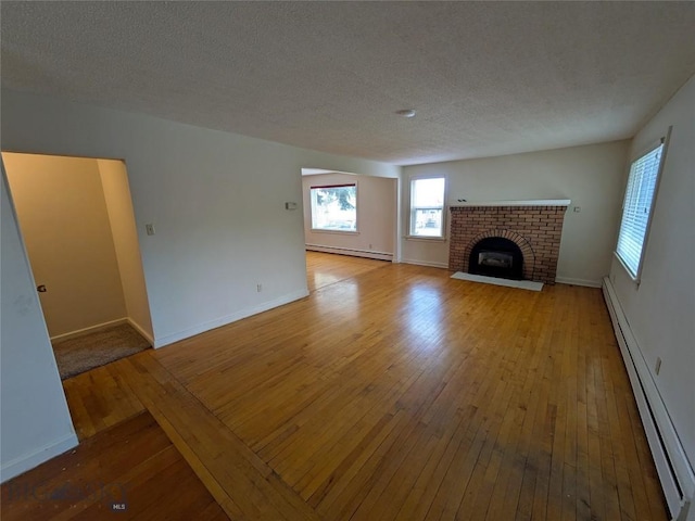 944 Placer, Butte, MT 59701 - unfurnished living room featuring a baseboard heating unit, hardwood / wood-style floors, baseboard heating, plenty of natural light, and a textured ceiling