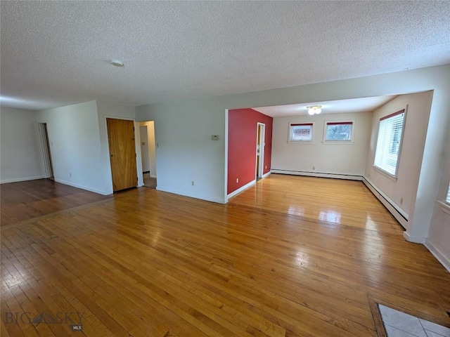 944 Placer, Butte, MT 59701 - unfurnished living room with hardwood / wood-style flooring, baseboard heating, and a textured ceiling