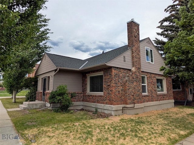 944 Placer, Butte, MT 59701 - view of home's exterior with a chimney, a yard, brick siding, and roof with shingles