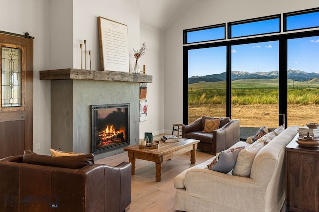 120 Horseshoe Loop, Harrison, MT 59735 - living room with light wood finished floors, a mountain view, a glass covered fireplace, and vaulted ceiling