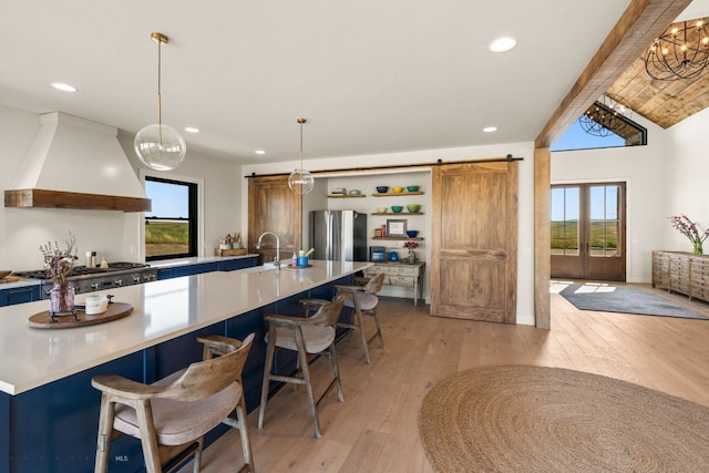 120 Horseshoe Loop, Harrison, MT 59735 - kitchen featuring a barn door, custom range hood, stainless steel appliances, open shelves, and a breakfast bar