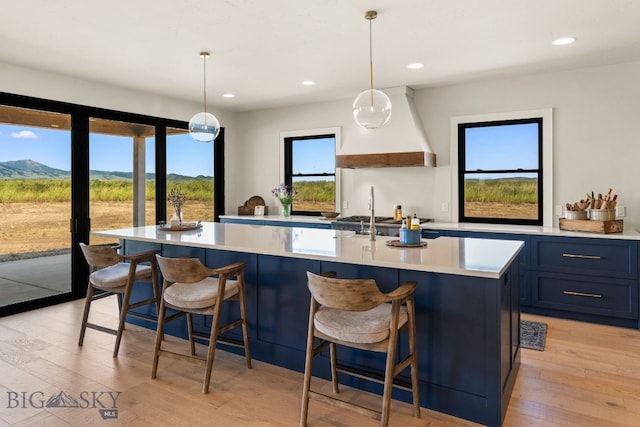 120 Horseshoe Loop, Harrison, MT 59735 - kitchen with light wood-style floors, light countertops, a kitchen island with sink, recessed lighting, and custom exhaust hood