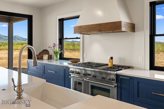 120 Horseshoe Loop, Harrison, MT 59735 - kitchen featuring premium range hood, double oven range, blue cabinetry, and light countertops