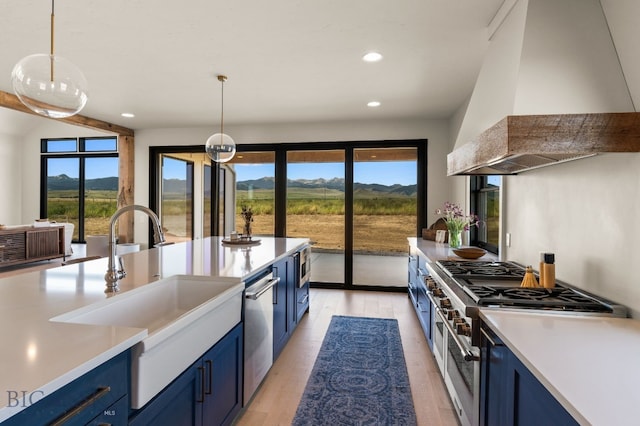 120 Horseshoe Loop, Harrison, MT 59735 - kitchen with blue cabinetry, custom exhaust hood, stainless steel appliances, healthy amount of natural light, and recessed lighting