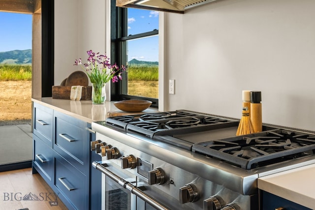 120 Horseshoe Loop, Harrison, MT 59735 - kitchen featuring blue cabinetry, double oven range, a mountain view, light wood finished floors, and light countertops