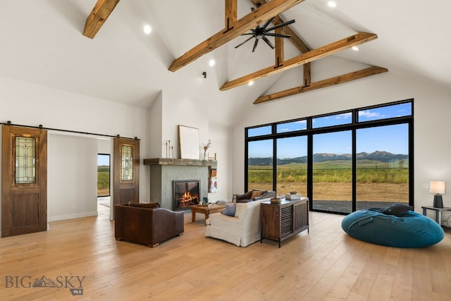 120 Horseshoe Loop, Harrison, MT 59735 - living area with high vaulted ceiling, beamed ceiling, light wood-style flooring, a glass covered fireplace, and healthy amount of natural light