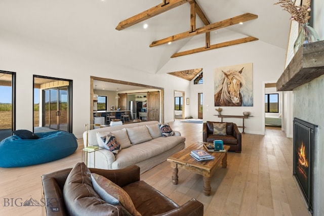 120 Horseshoe Loop, Harrison, MT 59735 - living room featuring high vaulted ceiling, beamed ceiling, a lit fireplace, light wood-style flooring, and recessed lighting