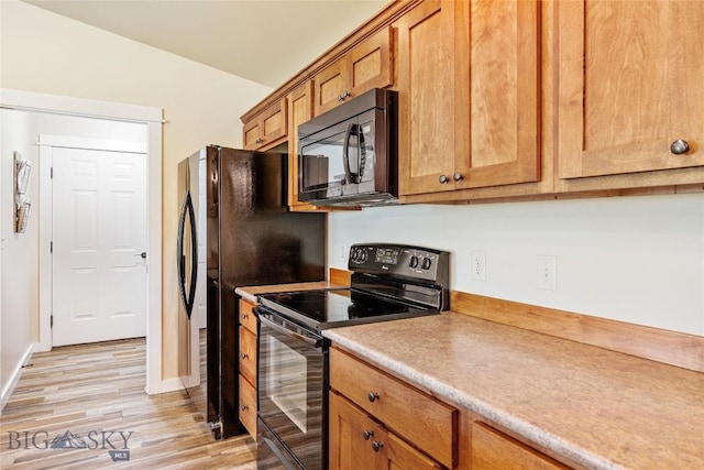 160 Tail Feather Ln Unit D, Bozeman, MT 59718 - kitchen featuring black appliances, light wood-type flooring, light countertops, brown cabinetry, and lofted ceiling