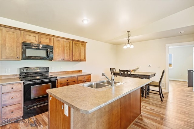160 Tail Feather Ln Unit D, Bozeman, MT 59718 - kitchen with black appliances, light wood finished floors, light countertops, a kitchen island with sink, and decorative light fixtures