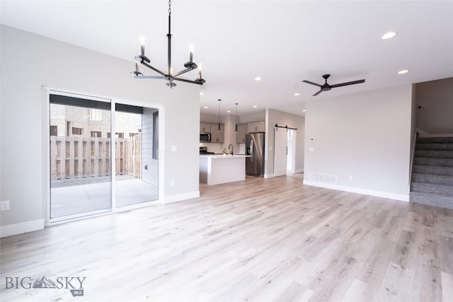 740 Rogers Way Unit B, Bozeman, MT 59718 - unfurnished living room featuring a barn door, a chandelier, light wood-style flooring, stairway, and recessed lighting